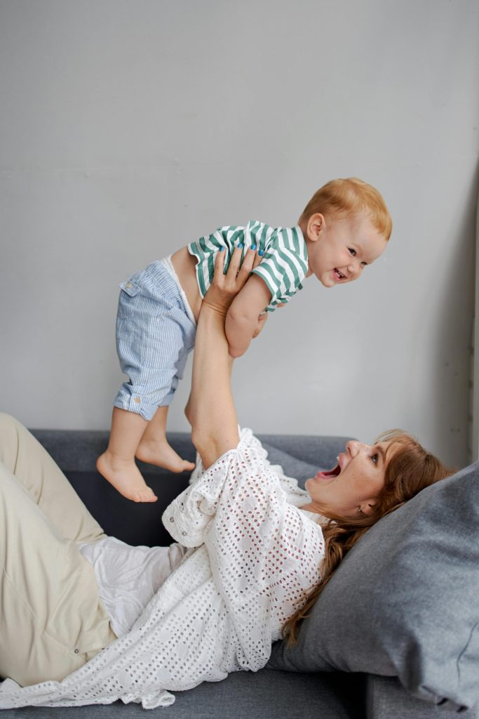 Une mère soulève avec tendresse son bébé souriant à l'intérieur, témoignant de son amour et de son bonheur.